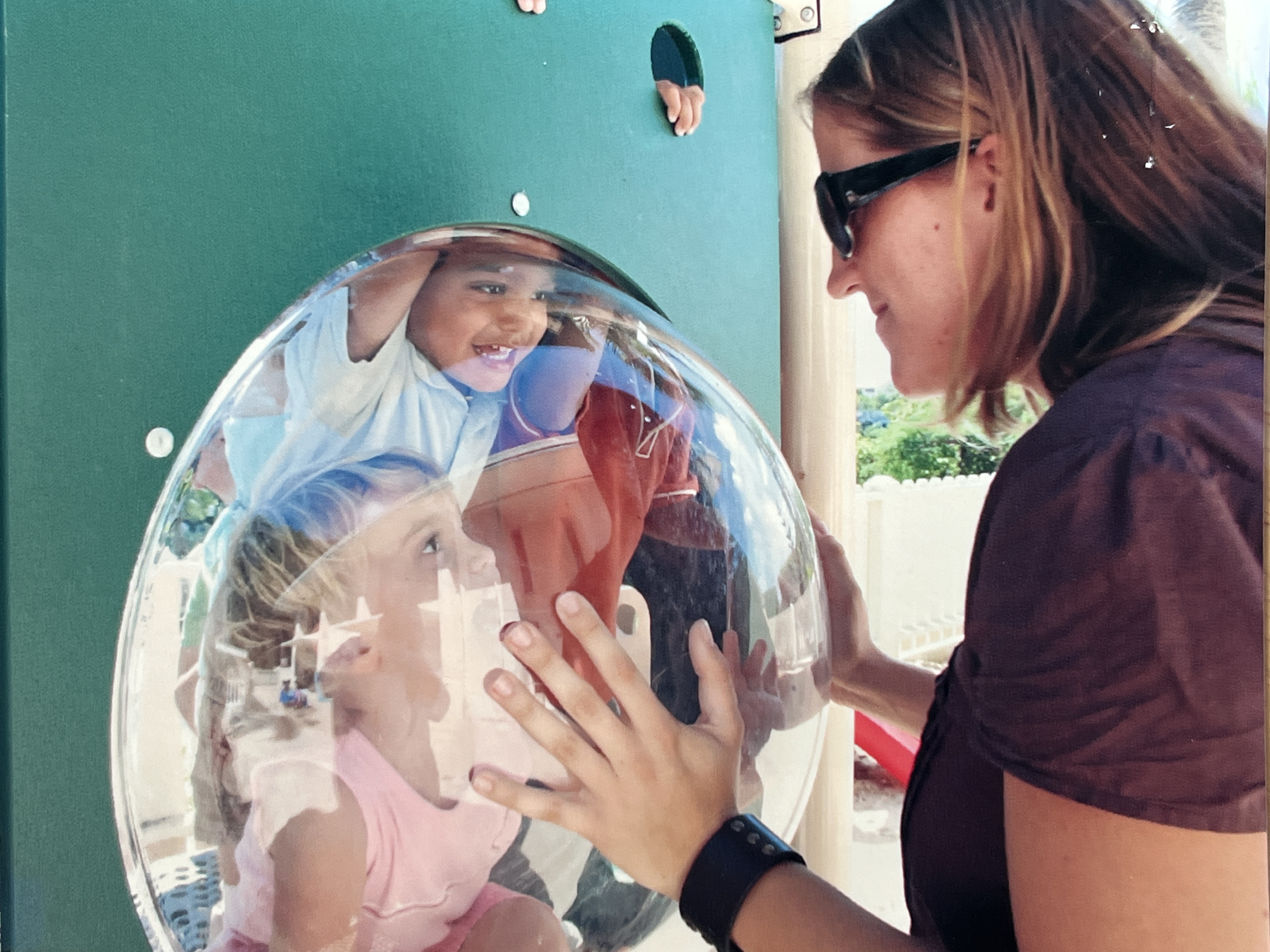 Young Antilles students and an educator exploring an outdoor play feature